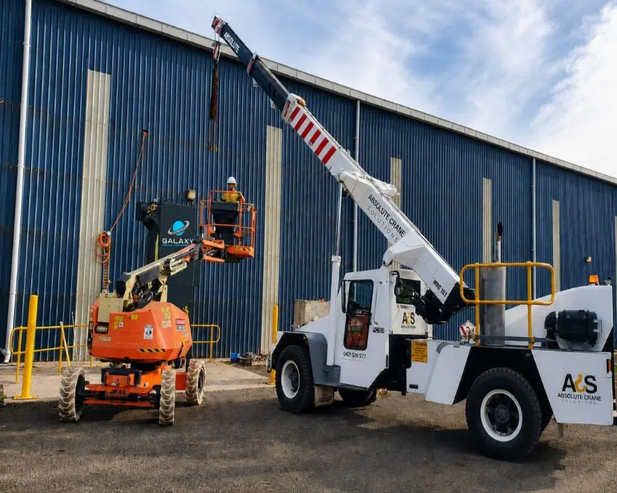Crane and boom lift coordinating equipment removal from industrial building